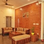 Warm and inviting living room featuring wooden furniture and a brick accent wall in Kerala, India.