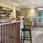 Stylish cafe interior in Thrissur, featuring modern wooden decor, plants, and seating.