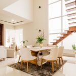 Stylish interior of spacious living room with minimalistic design with big windows and light furniture with wooden details